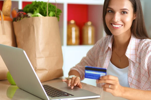 Femme souriante achats en ligne en utilisant tablette et carte de crédit dans la cuisine — Photo