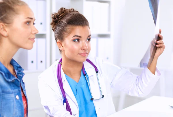 Jovem médica estudando radiografia sentada na mesa — Fotografia de Stock