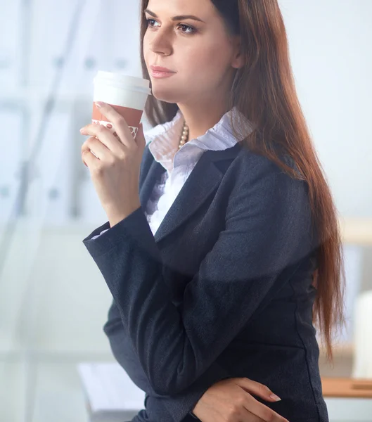 Schöne Geschäftsfrau genießt Kaffee im hellen Büro — Stockfoto