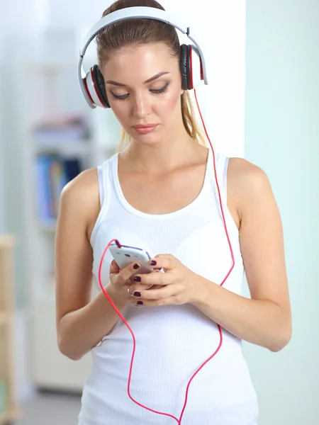 Женщина с наушниками слушает музыку стоя дома — стоковое фото