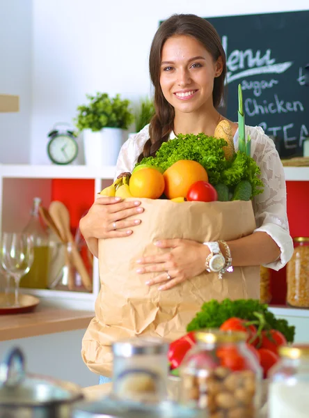 Elinde sebzeli alışveriş torbası tutan genç bir kadın. — Stok fotoğraf