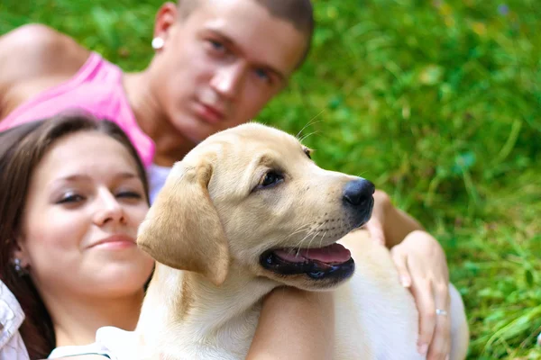 Una pareja sonriente con su perro al aire libre — Foto de Stock