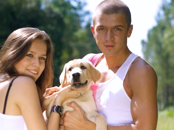 A smiling couple with their dog outdoors — Stock Photo, Image