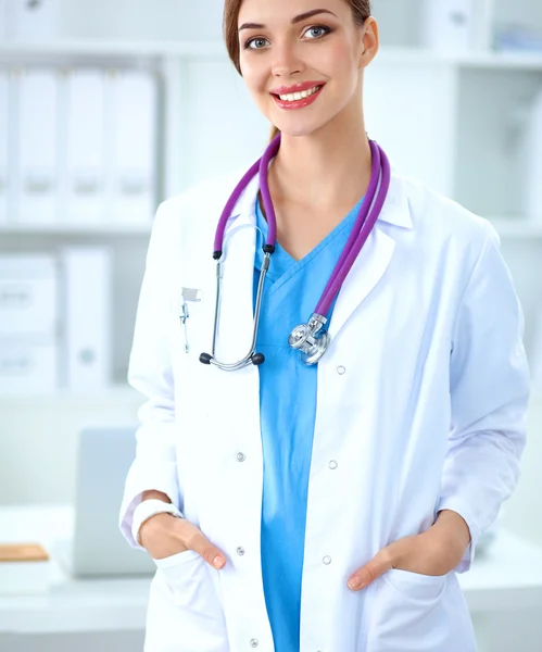 Portrait of young woman doctor with white coat standing in hospital Stock Picture