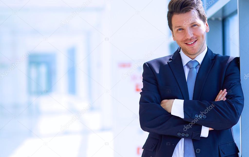 Portrait of businessman standing near window in office