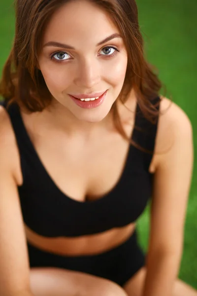 Woman sitting with crossed legs on the green grass — Stock Photo, Image