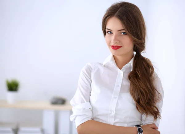 Attractive businesswoman standing near wall in office — Stock Photo, Image