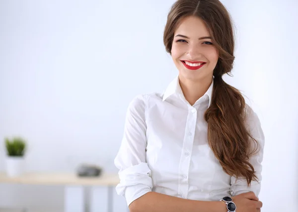 Attractive businesswoman standing near wall in office — Stock Photo, Image