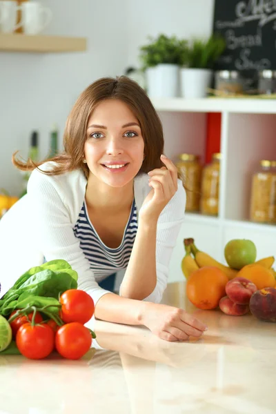 Mujer joven sentada cerca de escritorio en la cocina — Foto de Stock