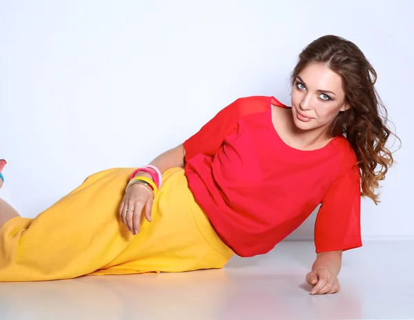 Young woman sitting on the floor, isolated in white background — Stock Photo, Image