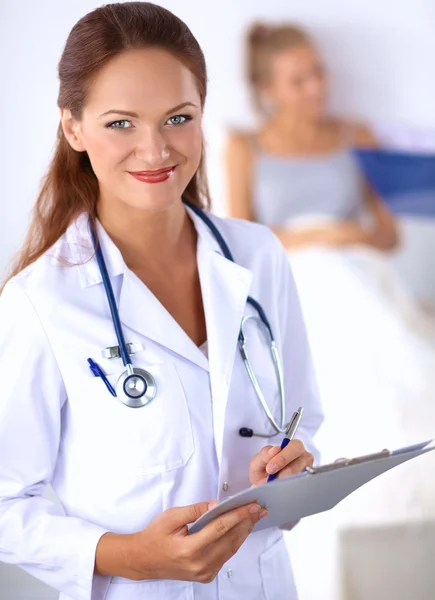 Médico sonriente con una carpeta en uniforme de pie en el hospital —  Fotos de Stock