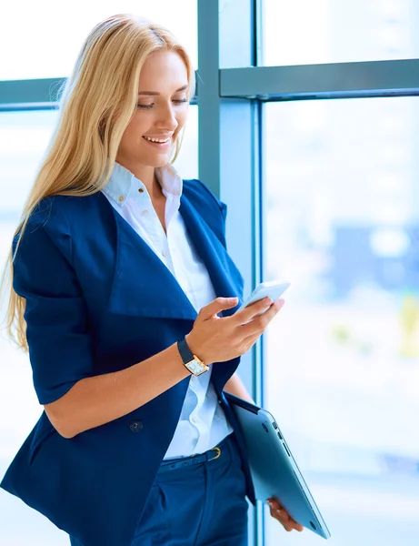 İş kadını ofis penceresinin önünde cep telefonuyla konuşuyor — Stok fotoğraf