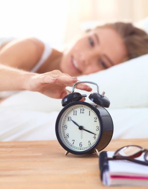 Evdeki yatak odasında uyuyan genç kadın ve çalar saat.