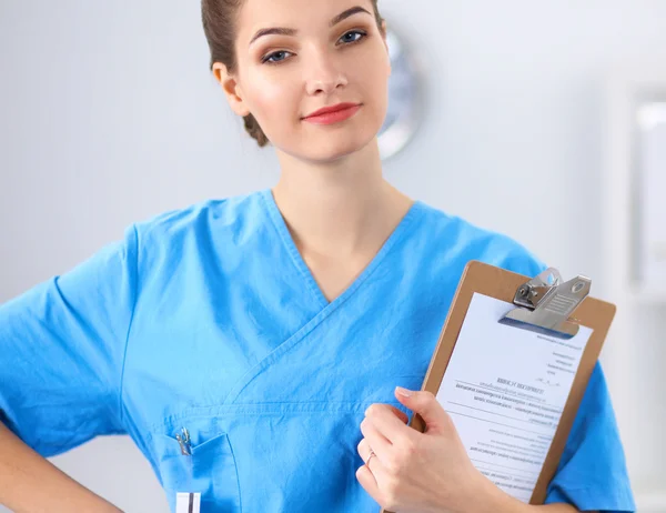 Lächelnde Ärztin mit Ordner in Uniform steht im Krankenhaus — Stockfoto