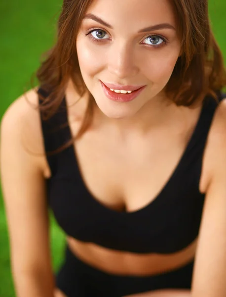 Vrouw zitten met gekruiste benen op het groene gras — Stockfoto