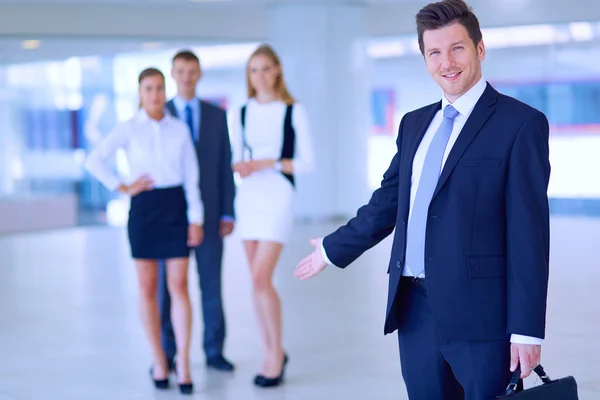 Portret van jonge zakenman in kantoor met collega's op de achtergrond — Stockfoto