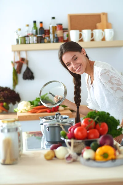 Mujer joven parada junto a la estufa en la cocina —  Fotos de Stock