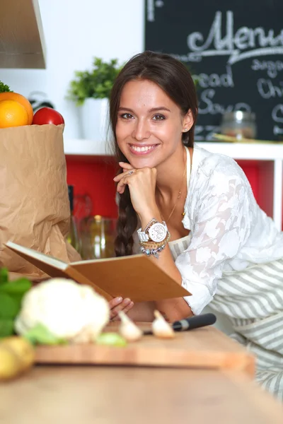 Jeune femme lecture livre de cuisine dans la cuisine, à la recherche de la recette — Photo