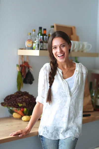 Jovem mulher de pé perto da mesa na cozinha — Fotografia de Stock