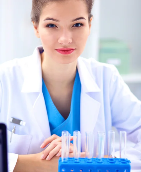 Woman researcher is surrounded by medical vials and flasks, isolated on white background — Stock Photo, Image