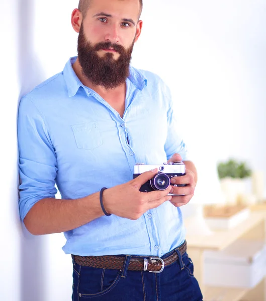 Young beard man holding a camera while standing against white background — Stock Photo, Image