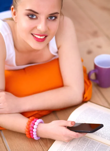 Lachende jonge vrouw liggend op een witte vloer met kussen — Stockfoto