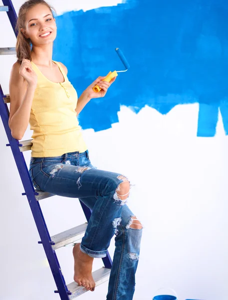 Happy beautiful young woman doing wall painting, standing near ladder — Stock Photo, Image