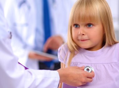 Kadın doktor ameliyatta steteskopla çocuğu muayene ediyor.