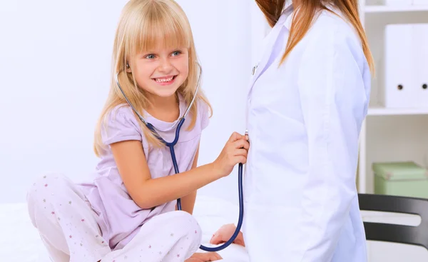 Vrouwelijke arts onderzoekt kind met stethoscoop bij chirurgie. — Stockfoto