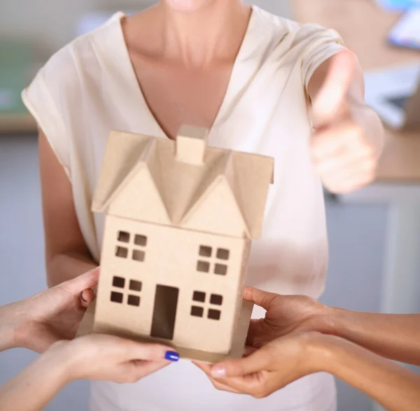 Retrato de una arquitecta sosteniendo una casita, de pie en la oficina — Foto de Stock