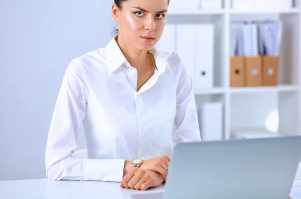 Attractive businesswoman sitting on a desk with laptop in the office — Stock Photo, Image