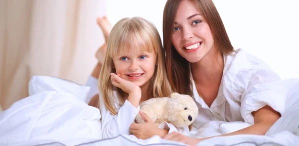 Woman and young girl lying in bed smiling — Stock Photo, Image