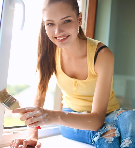 Woman painting wall of an apartment with a paintbrush carefully finishing off around  window frame — Stock Photo, Image