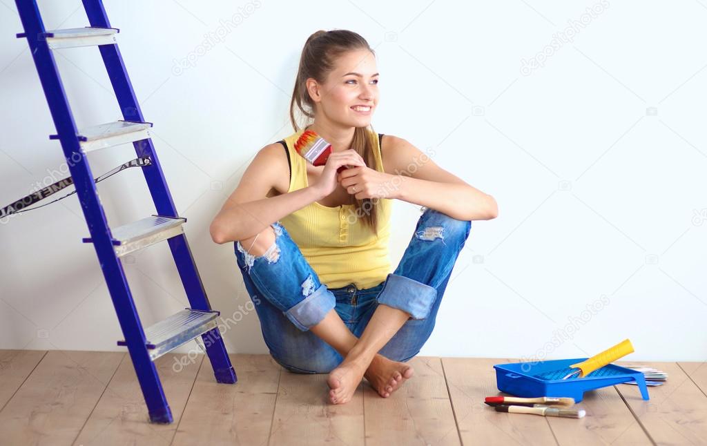 Portrait of female painter sitting on floor near wall after painting.