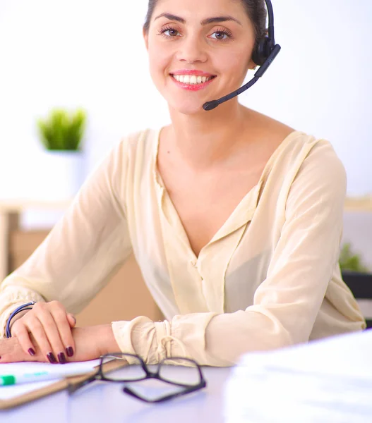 Porträtt av vacker affärskvinna som arbetar vid sitt skrivbord med headset och laptop — Stockfoto