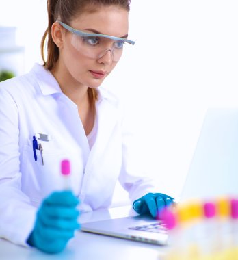 Kadın araştırmacı, beyaz şişeler ve şişelerle çevrili.