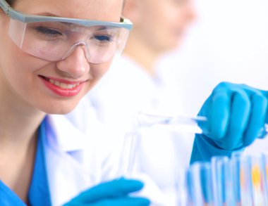 Kadın araştırmacı, beyaz şişeler ve şişelerle çevrili.