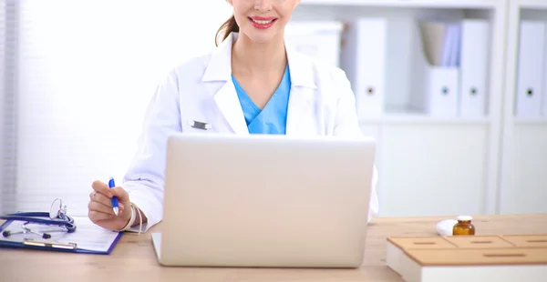 Female doctor sitting on the desk and working a laptop — Stock Photo, Image