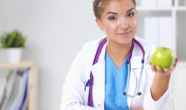 Mujer médico mano sosteniendo una manzana verde, sentado — Foto de Stock