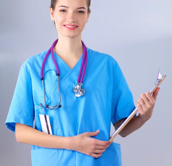 Lächelnde Ärztin mit Ordner in Uniform steht im Krankenhaus — Stockfoto