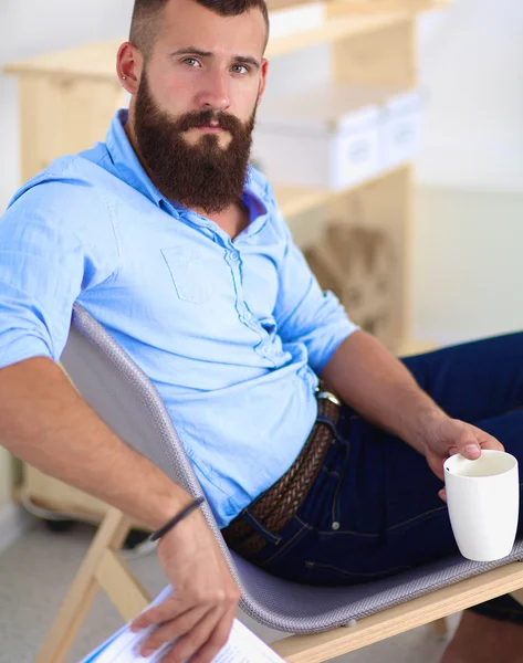 Giovane seduto con computer portatile e una tazza di tè a casa — Foto Stock