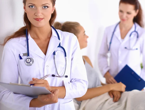 Médico sonriente con una carpeta en uniforme de pie en el hospital — Foto de Stock