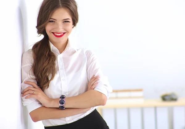 Attractive businesswoman standing near wall in office — Stock Photo, Image