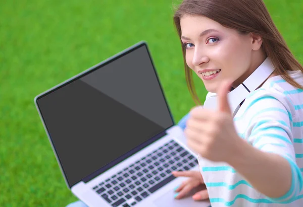 Young woman with laptop sitting on green grass — Stock Photo, Image