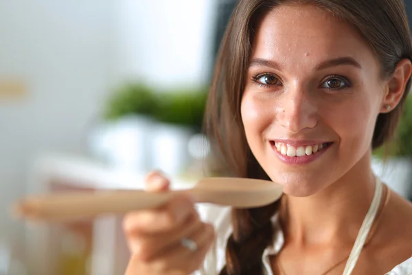 Mujer cocinera en cocina con cuchara de madera —  Fotos de Stock