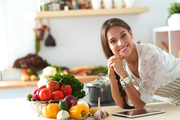 Jovem usando um computador tablet para cozinhar em sua cozinha — Fotografia de Stock