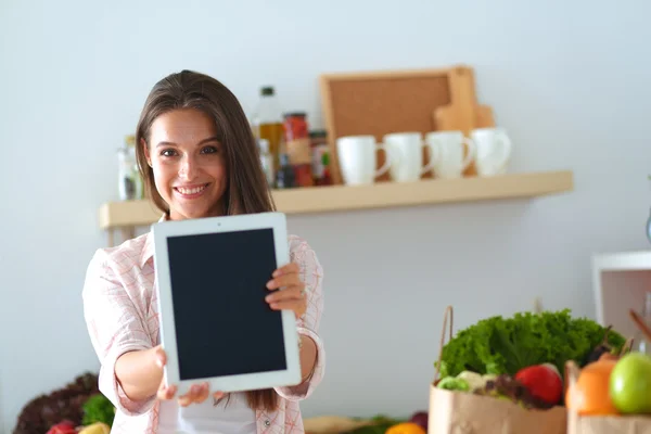 Mujer joven usando una tableta para cocinar en su cocina — Foto de Stock