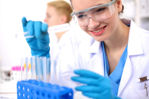 Woman researcher is surrounded by medical vials and flasks, isolated on white background — Stock Photo, Image