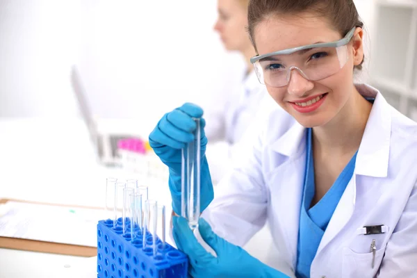 Woman researcher is surrounded by medical vials and flasks, isolated on white background — Stock Photo, Image