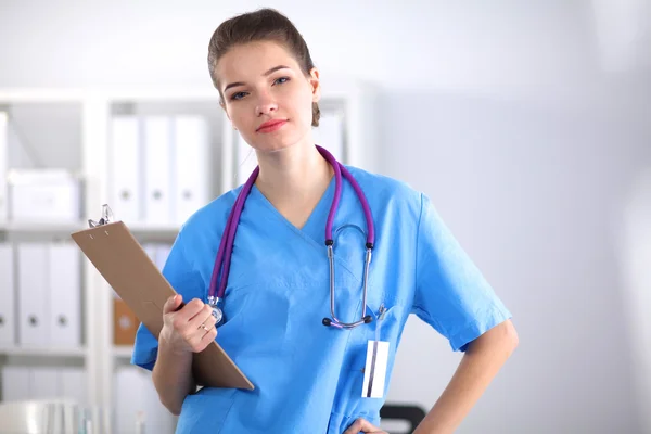 Lächelnde Ärztin mit Ordner in Uniform steht im Krankenhaus — Stockfoto